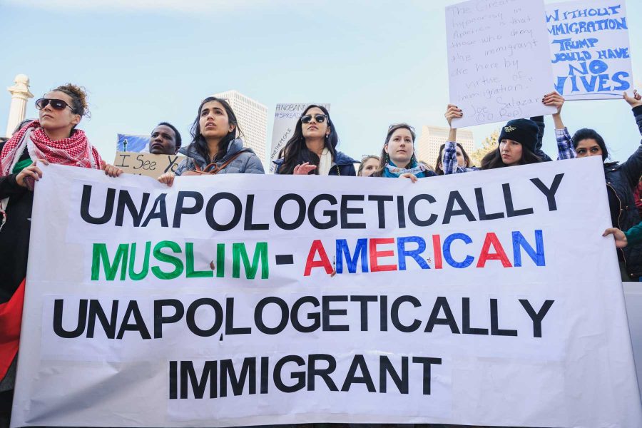 Rally participant help hold a sign supporting Muslims and immigrants in Denver during the Muslim and immigrant solidarity event hosted in Civic Center Park, February 4, 2017 (Davis Bonner | Collegian)