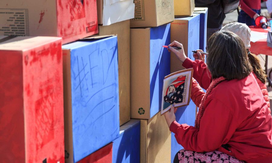 A passerby writes a message on College Republicans at CSU's 'Free Speech Wall' during the "To Immigrants With Love" event on the plaza. February 8, 2017 (Davis Bonner | Collegian)