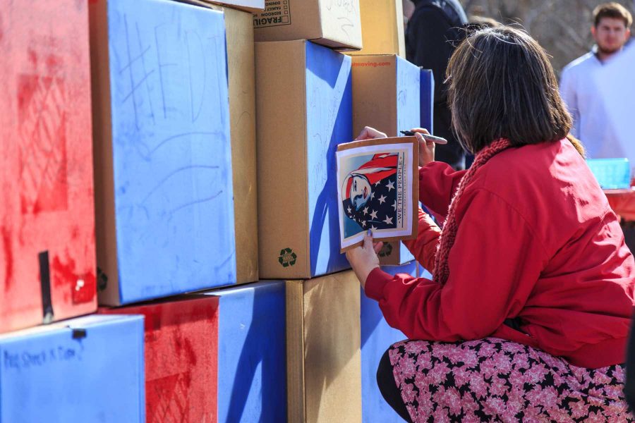 A passerby writes a message on College Republicans at CSU's 'Free Speech Wall' during the "To Immigrants With Love" event on the plaza. February 8, 2017 (Davis Bonner | Collegian)