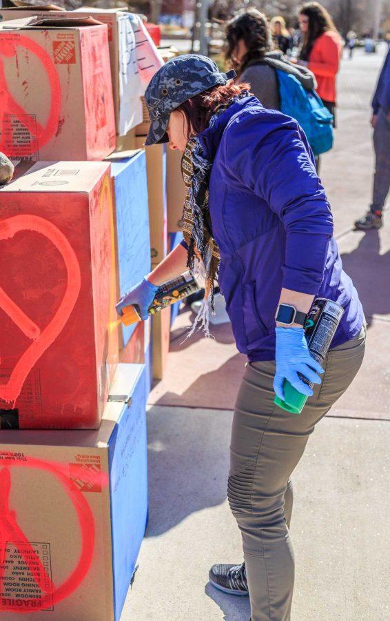Tana, a "veteran against Trump," spray paints hearts and peace symbols on College Republicans at CSU's 'Free Speech Wall' during the "To Immigrants With Love" event hosted by Dreamers United. February 8, 2017 (Davis Bonner | Collegian)