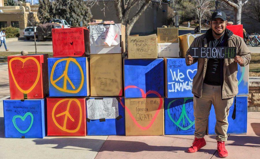 Alex Marquez holds his "I Belong Here" sign as he stands in front of College Republicans at CSU's 'Free Speech Wall' covered in messages from students on the plaza.  (Davis Bonner | Collegian)