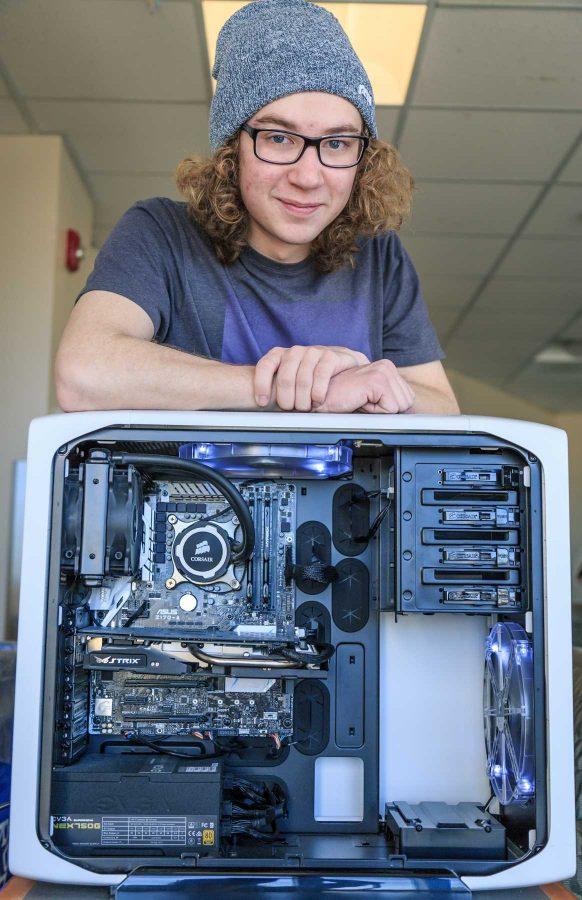 Caleb Carpenter, a freshman computer science major stands with his beloved computer he built at the beginning of the school year. Caleb says they "spend a lot of time together" with favorite activities including listening to music and playing video games (Davis Bonner | Collegian)