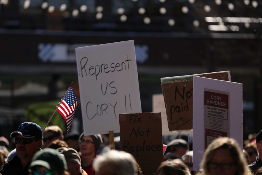 An American flag is pictured among various types of political signs during a rally against Colorado Senator Cory Gardner in downtown Fort Collins on Sunday afternoon. (Forrest Czarnecki | Collegian)