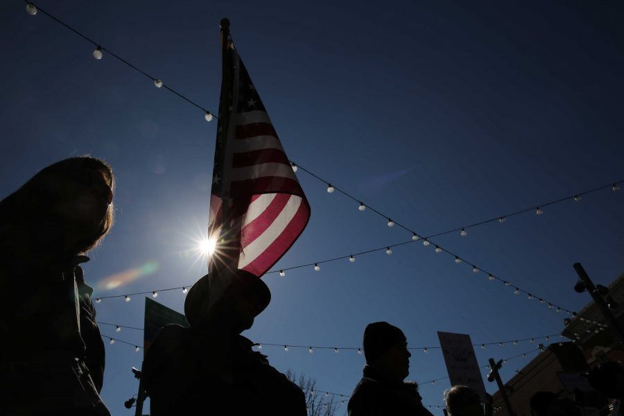 Jim Berry holds an American flag while cheering with the crowd at a rally against Colorado Senator Cory Gardner in downtown Fort Collins on Sunday afternoon. (Forrest Czarnecki | Collegian)