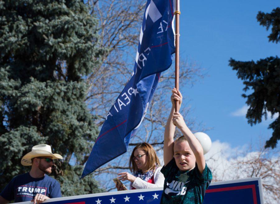Brycen Thomas waves a Trump flag while his parents, Ryan and Chelsea Thomas, hold a large sign at the March 4 Trump rally in Denver on Saturday. Photo by Kaitlyn Ancell | Collegian
