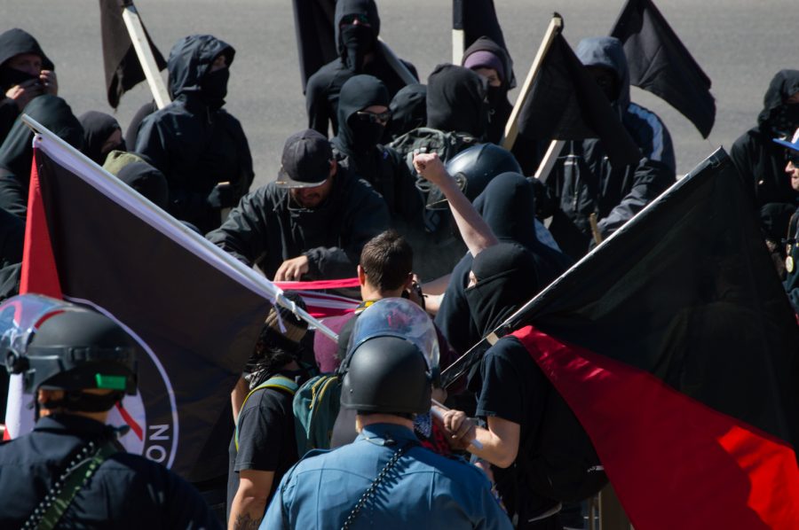 The ANTIFA protestors rip a flag in a demonstration against Trump at the March 4 Trump rally in Denver on Saturday. Photo by Kaitlyn Ancell | Collegian