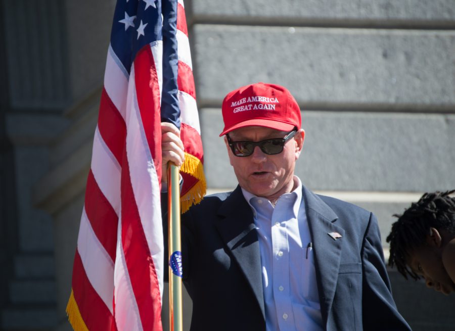 Mike McAlpine carries the flag in front of the State Capitol building at the March 4 Trump rally in Denver on Saturday. Photo by Kaitlyn Ancell | Collegian