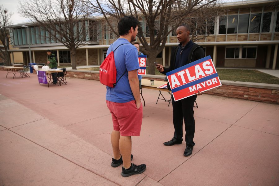Kwon Atlas, with sign, speaks to Colorado State University student Bronson Torres about his mayoral campaign in the Plaza on Friday morning. (Forrest Czarnecki | Collegian)