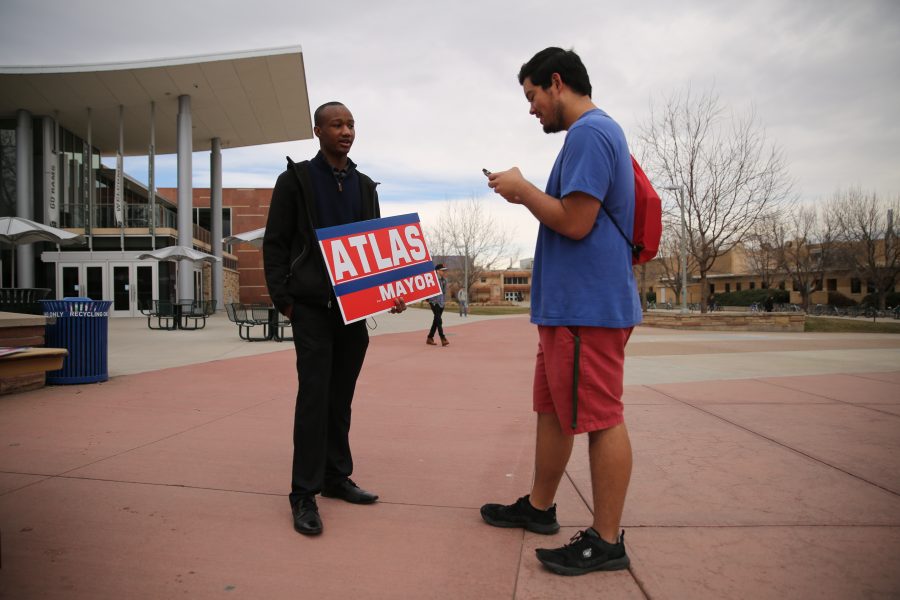 Kwon Atlas, with sign, speaks to Colorado State University student Bronson Torres about his mayoral campaign in the Plaza on Friday morning. (Forrest Czarnecki | Collegian)