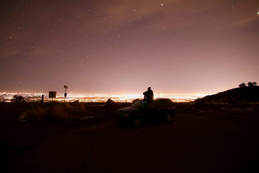 Mitch Howard sits on top of his car at Horsetooth Reservoir overlooking the lights of Fort Collins, March 2017. (Collegian file photo)
