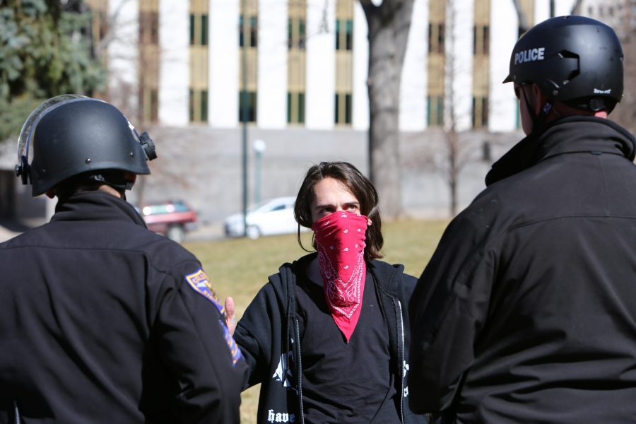 A protester against the Trump rally held at the capital building faces off against Colorado State Patrol officers. (Davis Bonner | Collegian)