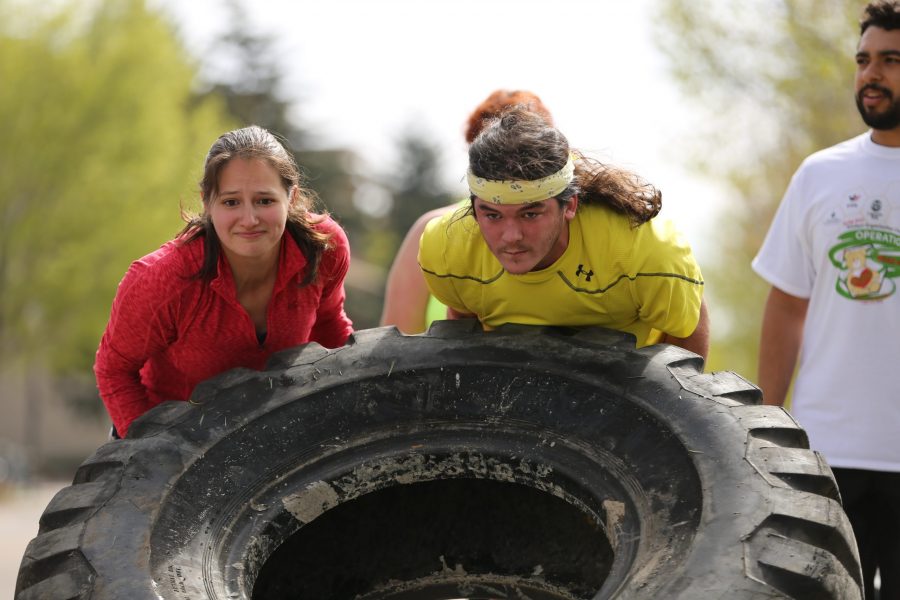Katie Santos, left, and Ryan Whitesell, right, flip a tractor tire down a sidewalk to a checkpoint while taking part in the Operation Bear Hug obstacle course 5K run on Sunday morning at Colorado State University.  (Forrest Czarnecki | Collegian)