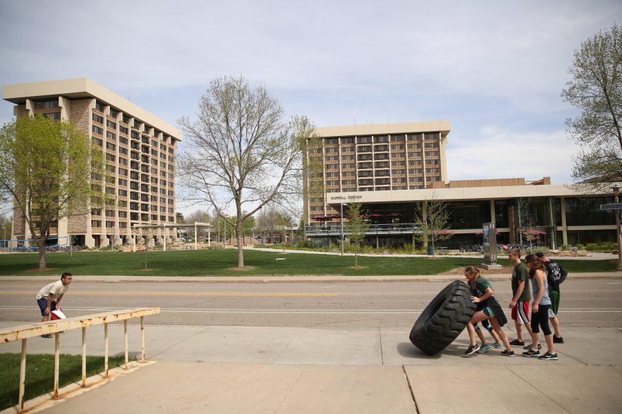 Competitors flip a tractor tire down the sidewalk on Plum Street while taking part in the Operation Bear Hug obstacle course 5K run on Sunday morning at Colorado State University.  (Forrest Czarnecki | Collegian)