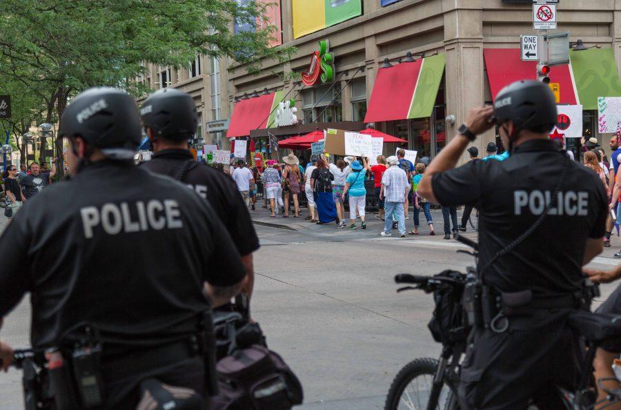 Under heavy police supervision, protesters pass through the 16th Street Mall during the Trump Impeachment March. (Davis Bonner | Collegian)