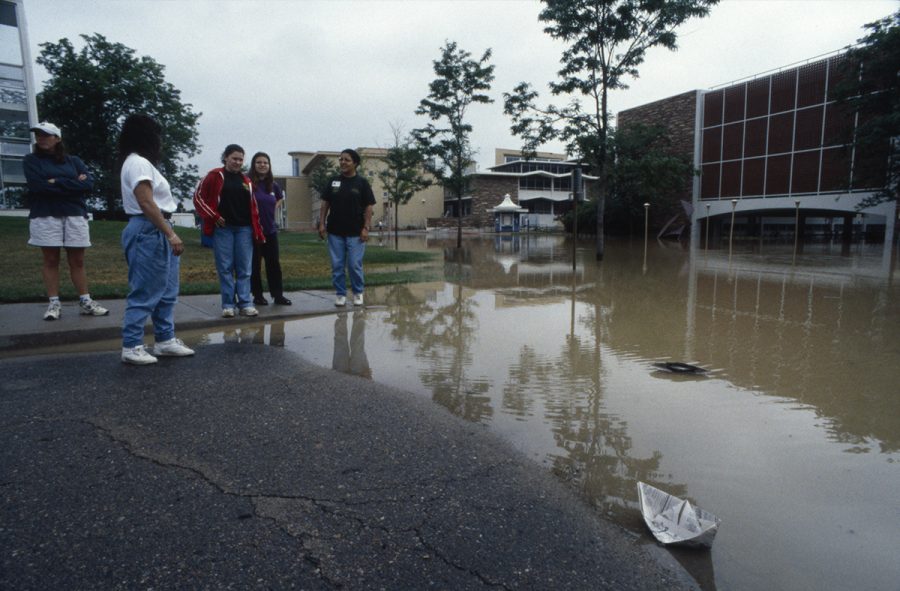 Five men and women stand on the west side of the Eddy building following the Spring Creek flood. (Photo courtesy of University Historic Photographic Collection, CSU Libraries, Archives & Special Collection)