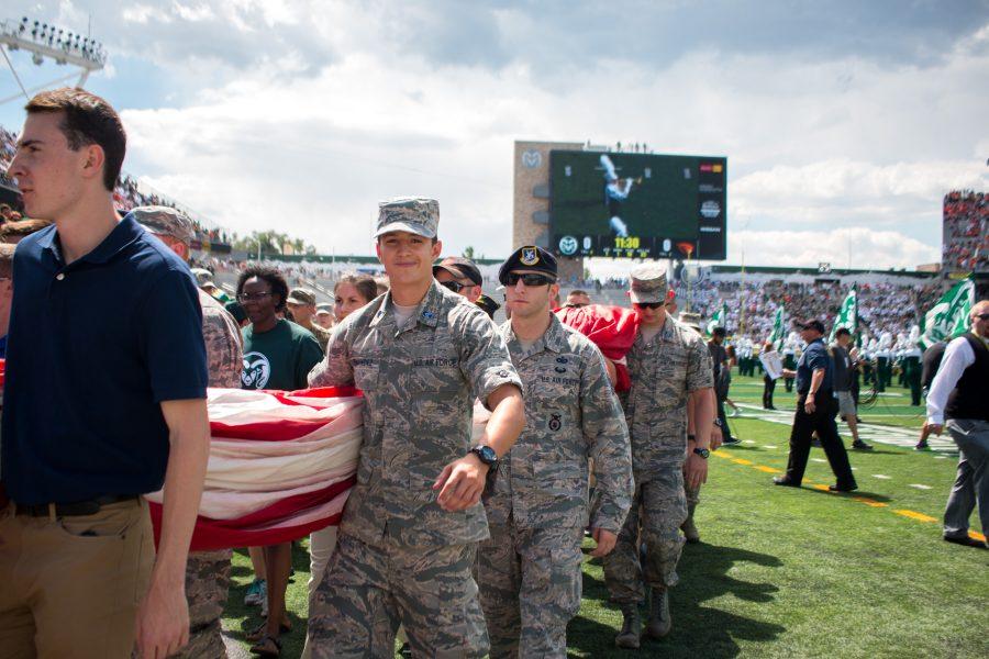 Military personnel carry the American flag off the field after the singing of the National Anthem at the new on-campus stadium. . (Jack Starkebaum | Collegian)