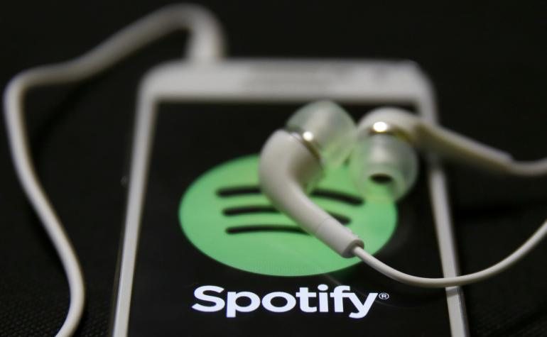 Headphones sit on a phone displaying the Spotify app. (Photo Courtesy of Flickr user download source.fr)