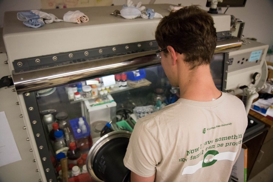 Nathan Gimble, a second year graduate student in Dr Prieto's lab, does his chemistry in an argon filled box. This box, filled with argon gas, allows scientists to create reactions without the interference of air or water, due to some compounds reactivity with elements like oxygen. Gimble studies particles a thousand times smaller than a human hair, nanoparticles,
 for potential uses as a semiconductor for harvesting solar energy.
 (Julia Trowbridge | Collegian)