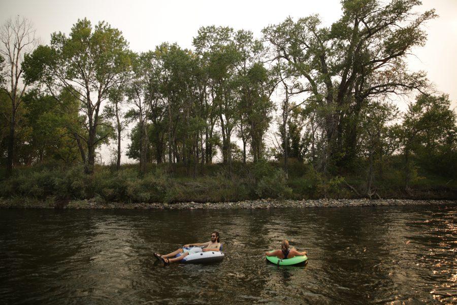 A pair of inner tubers ride on the Poudre River at sunset as it flows through Fort Collins on Sept. 4, 2017. (Forrest Czarnecki | The Collegian)