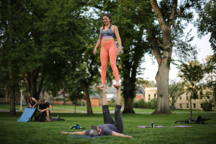 Colorado State University senior Mikaela Maldonado, top, and Garrett Dewey, bottom, perform an acroyoga pose during a yoga session at the Oval on the evening of September 7th. (Forrest Czarnecki | The Collegian)