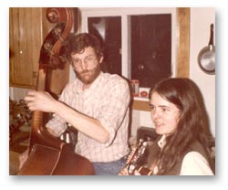 Curt Amason playing the upright bass and Ellen Audley playing the mandolin in a kitchen