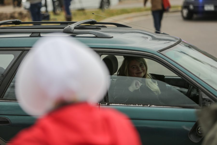 An attendee entering the Republican Party Fundraiser and a protestor dressed as a handmaid lock eyes. The protestors dressed in costume did so in reference to the popular television show Handmaids Tale that describes a world in which women are considered property. (Davis Bonner | Collegian)