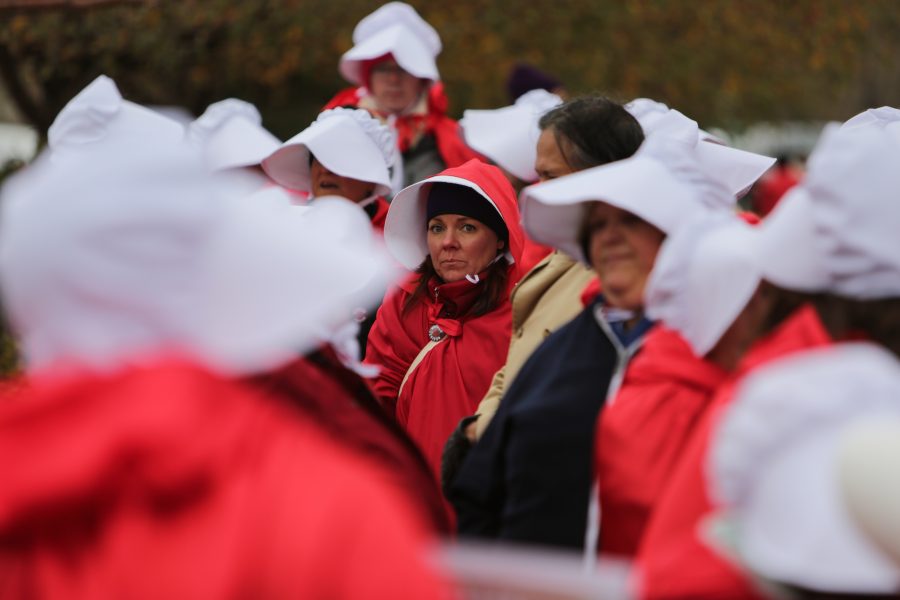 Molly McCallum stands with the crowd of other handmaids outside the Denver Marriott Tech Center where Vice President Mike Pence is to give a speech at a Republican Party fundraiser. The costumes are in reference to the popular television show Handmaids Tale that describes a world in which women are considered property. (Davis Bonner | Collegian)