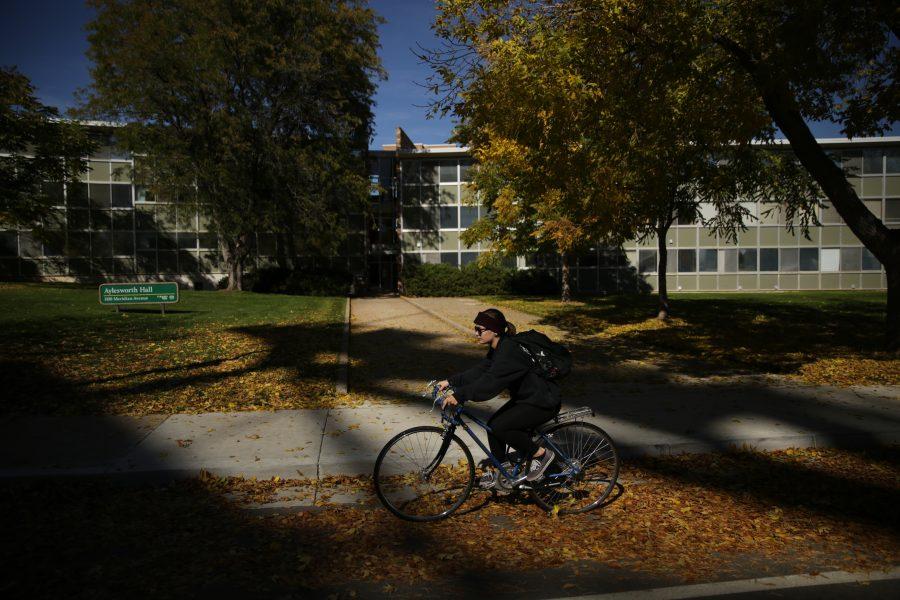 A student rides their bike through the leaves in front of Aylesworth Hall on Tuesday afternoon. The hall is currently involved in talks of being torn down. (Forrest Czarnecki | The Collegian)