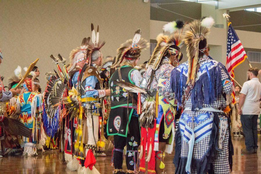 A group of mens dancers stand in honor of the colors during the beginning of the 35th Annual ASIES Pow Wow on Saturday, Nov. 4. (Ashley Potts | Collegian)