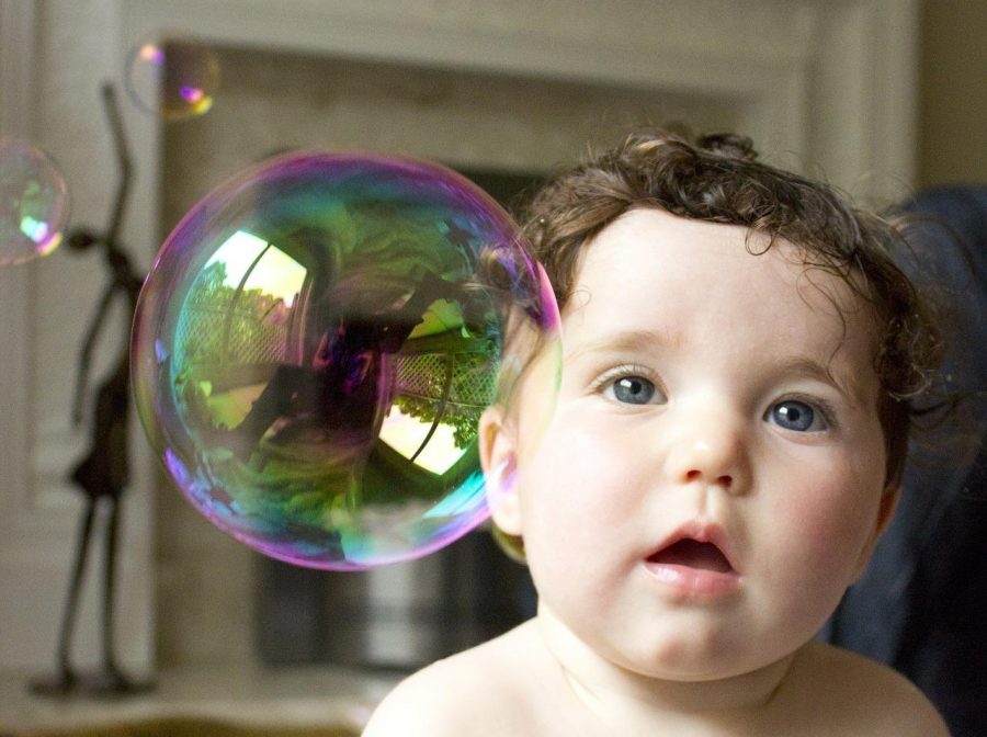 A child, next to a bubble, looks at the camera. Photo provided by Sally Wynn via pixabay. 
