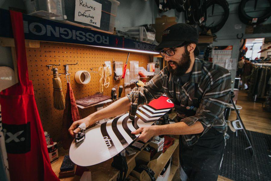 Ethan Solomon tunes up a snowboard at Gearage Outdoor Sports on Thursday, January 18, 2018. Solomon has worked at Gearage Outdoor Sports for about a month, and when asked what his favorite part about working there was, he said “I love learning about new equipment because something new and different always comes in.” Gearage Outdoor Sports is located in Old Town, and sells a variety of new and used outdoor gear and clothing. In addition, they provide tune ups for bikes and ski gear. (Colin Shepherd | Collegian)