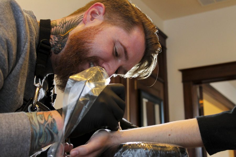 Todd Larson tattoos a semi-colon on Nate Day Tuesday afternoon in Old Town Fort Collins. (Jon Price | Collegian)