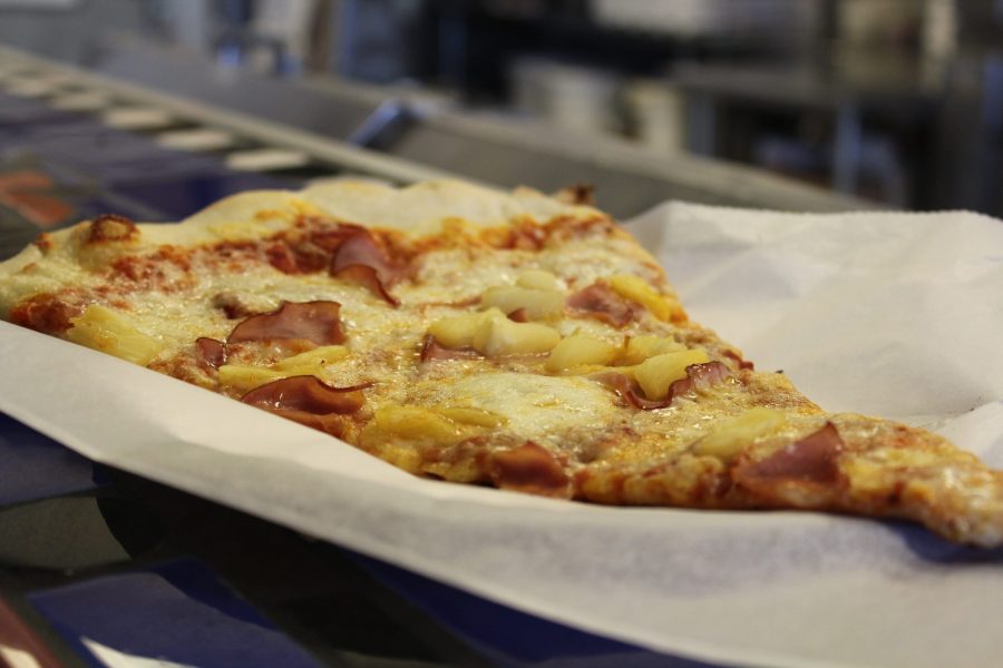 A Hawaiian pizza is served to a customer at Cosmos Pizza during lunch on a Sunday afternoon. The Hawaiian pizza is a cheese pizza topped with pineapple and ham. It is said by Vincent who is one of the cooks that it is very popular among customers. (Matt Begeman | Collegian)