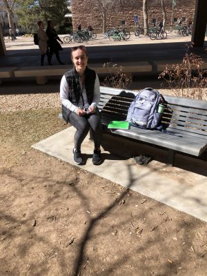 A student sits on a bench in the courtyard of the Clark Building