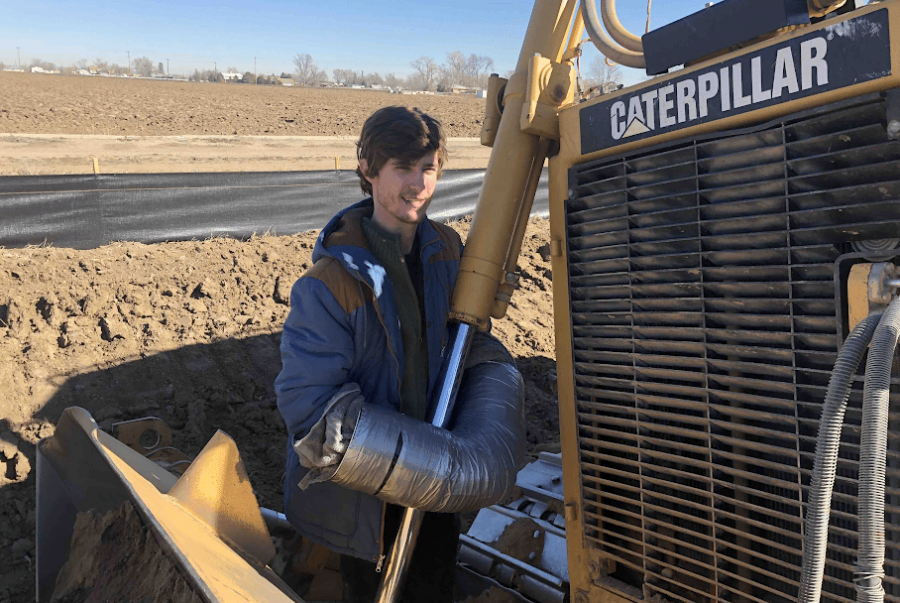 Cullen Lobe, a journalism and environmental affairs transfer student at CSU, is chained to a front end loader at the construction site of the Extraction Oil & Gas site in Greeley in an act of protest. Lobe was arrested for refusing to leave the construction site. (Photo courtesy of Cullen Lobe)