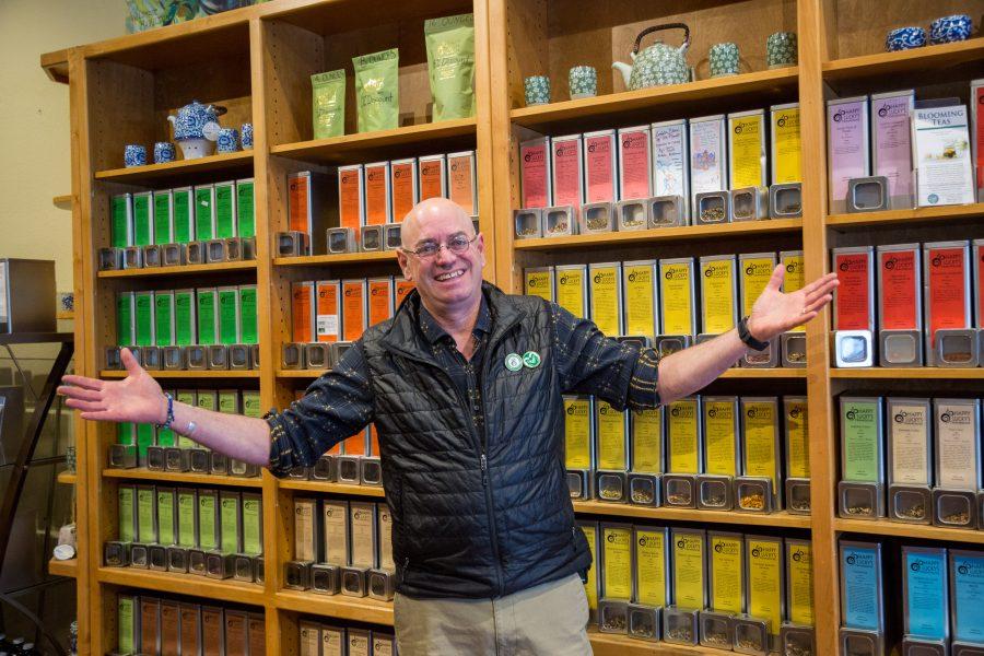 George Grossman, the owner and chief leafster at Happy Luckys Teahouse stands in front of the great wall of tea that contains roughly 200 different types and blends of tea. (Davis Bonner | Collegian)