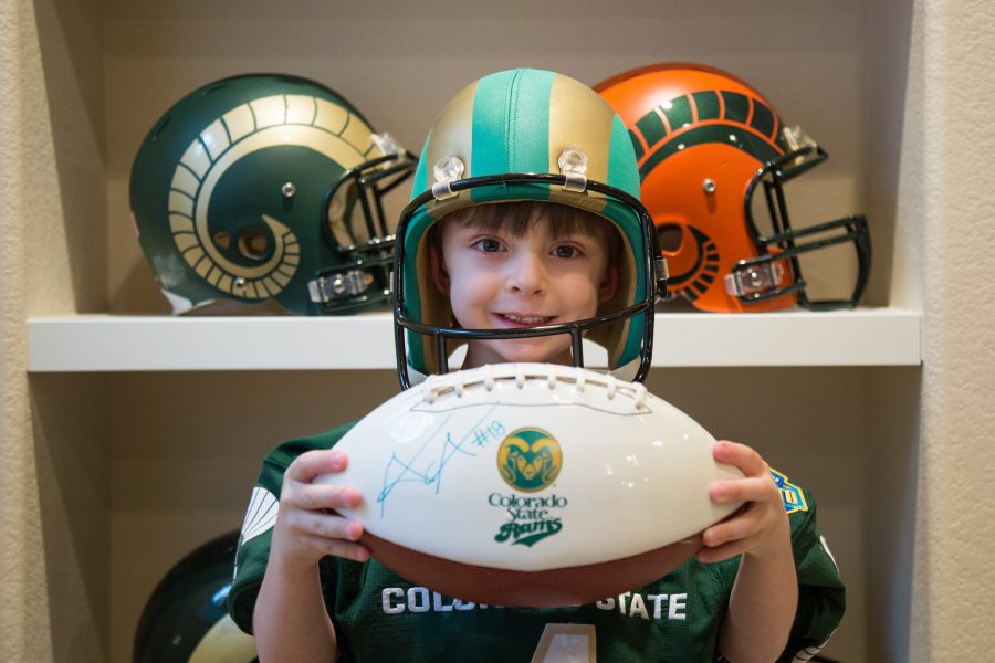 Bryce Krisl stands in front of his fathers custom helmets wearing the signed jersey given to him by Colorado State wide receiver Michael Gallup. Bryce has been attending CSU home games since he was two months old. (Davis Bonner | Collegian)