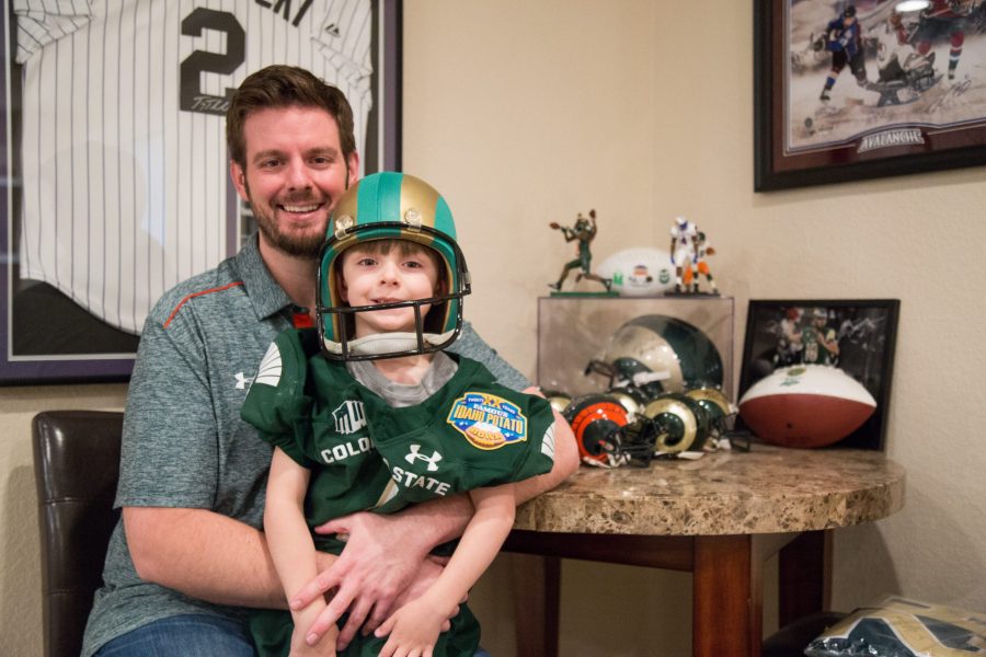 Bryce Krisl sits on his father Lance Krisls lap wearing the signed jersey given to him by Colorado State wide receiver Michael Gallup. Bryce has been attending CSU home games since he was two months old. (Davis Bonner | Collegian)