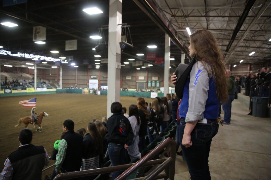 The United States Air Force Academy's Kate Everts holds her hat over her heart as the U.S. flag is shown before the start of the 68th annual Skyline Stampede rodeo on April 7, 2018 at the B.W. Pickett Arena in Fort Collins.  (Forrest Czarnecki | The Collegian)
