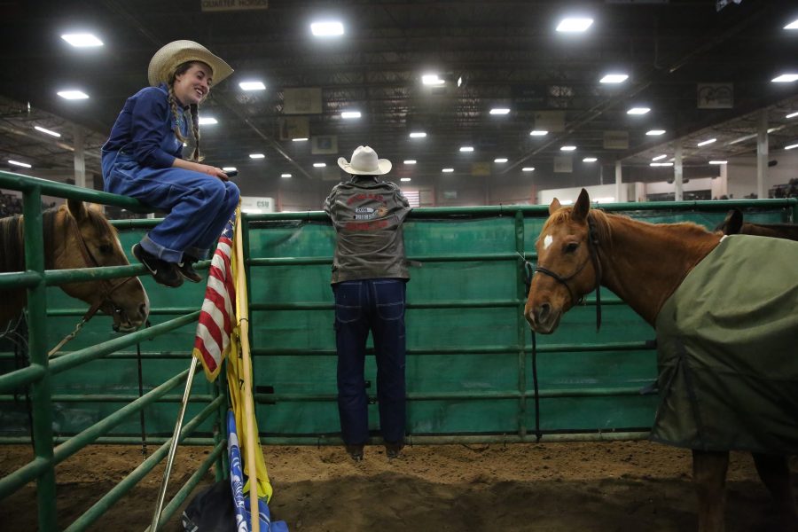 Faith Hoffman, on railing, laughs while her friend Ty Milleson, right, watches the 68th annual Skyline Stampede rodeo on April 7, 2018 at the B.W. Pickett Arena in Fort Collins.  (Forrest Czarnecki | The Collegian)