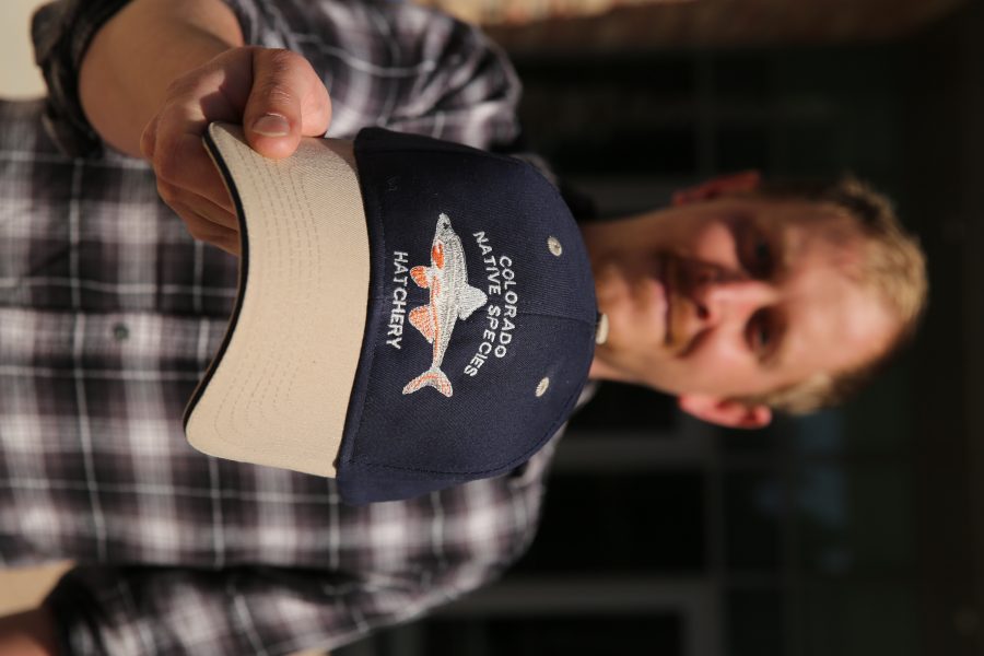 Chris Kopack holds a baseball hat with the "Colorado Native Fish Hatchery" logo on it. Kopack was recently awarded a fellowship from the National Science Foundation's Graduate Research Fellowship Program that will help him continue his graduate research. Kopack is doing his graduate work on native fish species in Colorado.  (Forrest Czarnecki | The Collegian)