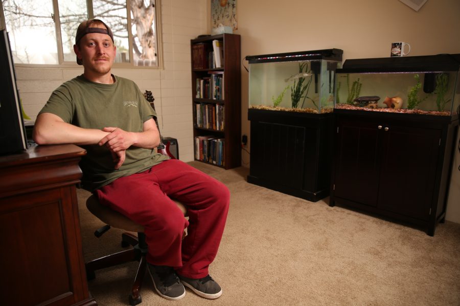 Chris Kopack poses for a portrait inside his home office in Fort Collins, where he keeps two large aquariums with freshwater fish species from his graduate work. The fish Kopack has at his home are muskelunge, which are large predatory fish, and Arkansas Darters, a smaller fish that's native to Colorado. Kopack was recently awarded a fellowship from the National Science Foundation's Graduate Research Fellowship Program that will help him continue his graduate research. Kopack is doing his graduate work on native fish species in Colorado.  (Forrest Czarnecki | The Collegian)