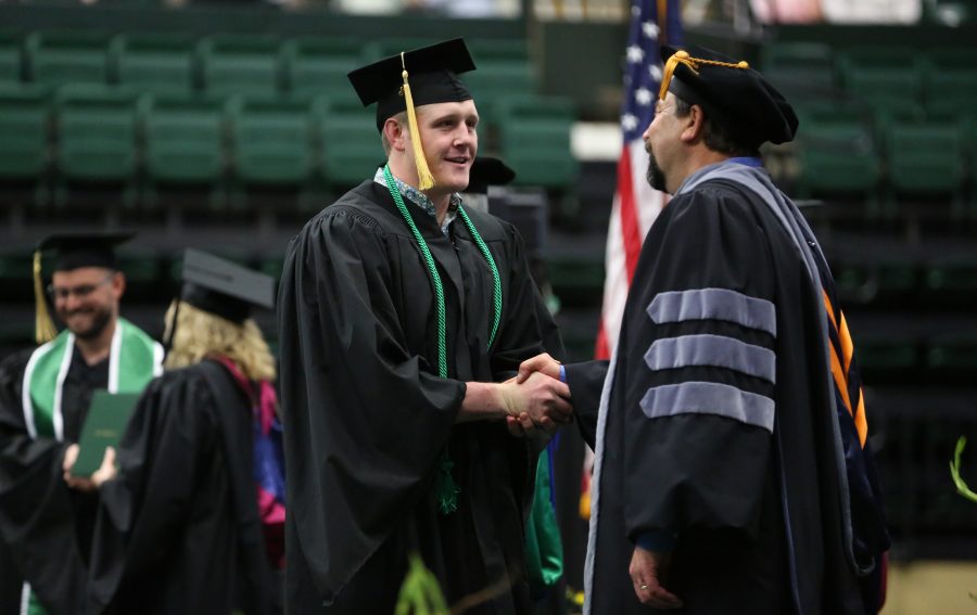 A Colorado State University graduate, left,  shakes the hand of Tony Frank, right, during the graduation ceremony for the College of Agricultural Sciences on May 12, 2018 at Moby Arena.  (Forrest Czarnecki | The Collegian)