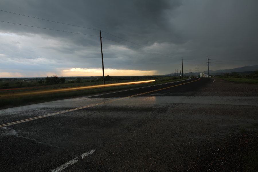The headlights of a passing car are seen moving over a washout stream crosses a county road west of town after a large thunderstorm passed through on May 22, 2018. The storm brought heavy rain, hail and lots of lightning.  (Forrest Czarnecki | The Collegian)