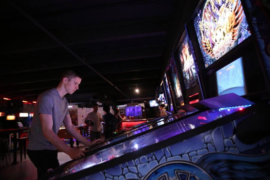Elliott Layne plays a game of pinball at the Pinball Jones Campus West location during the last night of the summer league.  (Forrest Czarnecki | The Collegian)