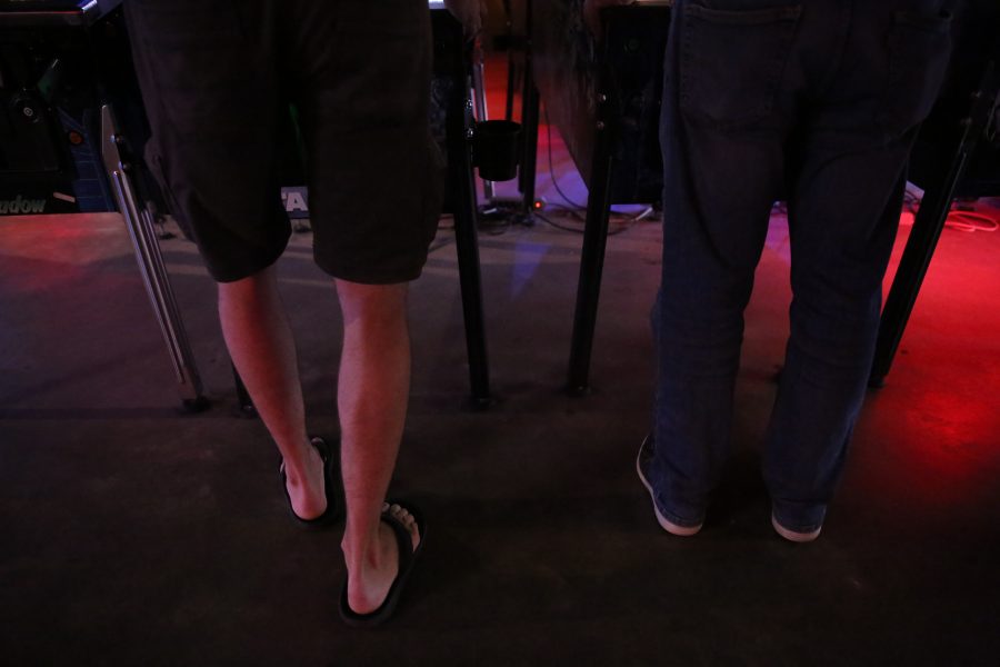 Two players compete next to each other in a game of pinball at the Pinball Jones Camus West location. The stance of a player is very important, and there are many different types of stances, according to Kim Jones.  (Forrest Czarnecki | The Collegian)