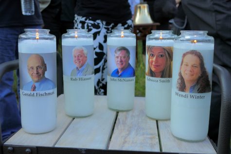 Candles honoring Gerald Fischman, Rob Hiassen, John McNamara, Rebecca Smith, and Wendi Winters flicker as the sun sets during a candlelight vigil on Friday, June 29, 2018, at Annapolis Mall for the five Capital Gazette employees slain during a shooting spree in their newsroom. (Karl Merton Ferron/Baltimore Sun/TNS)