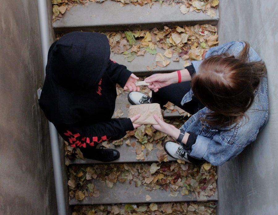 Two students exchange drugs in a abandoned stairway. (Collegian Photo Illustration)