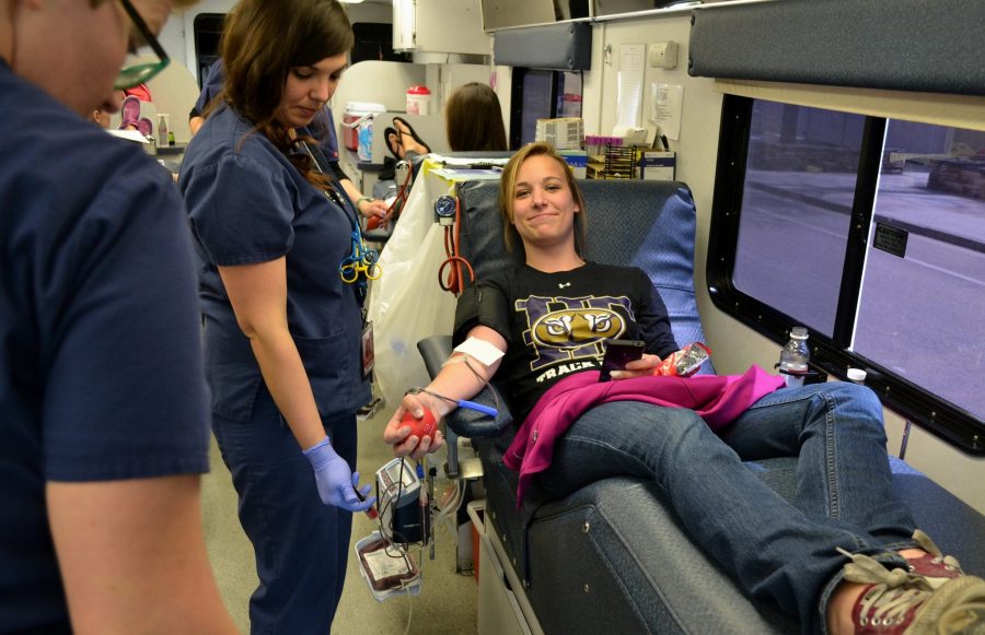Jay Kailey, a second year nursing student, donates blood with a proud smile at the onsite Bonfills Blood Donation bus just outside the Warner College building.