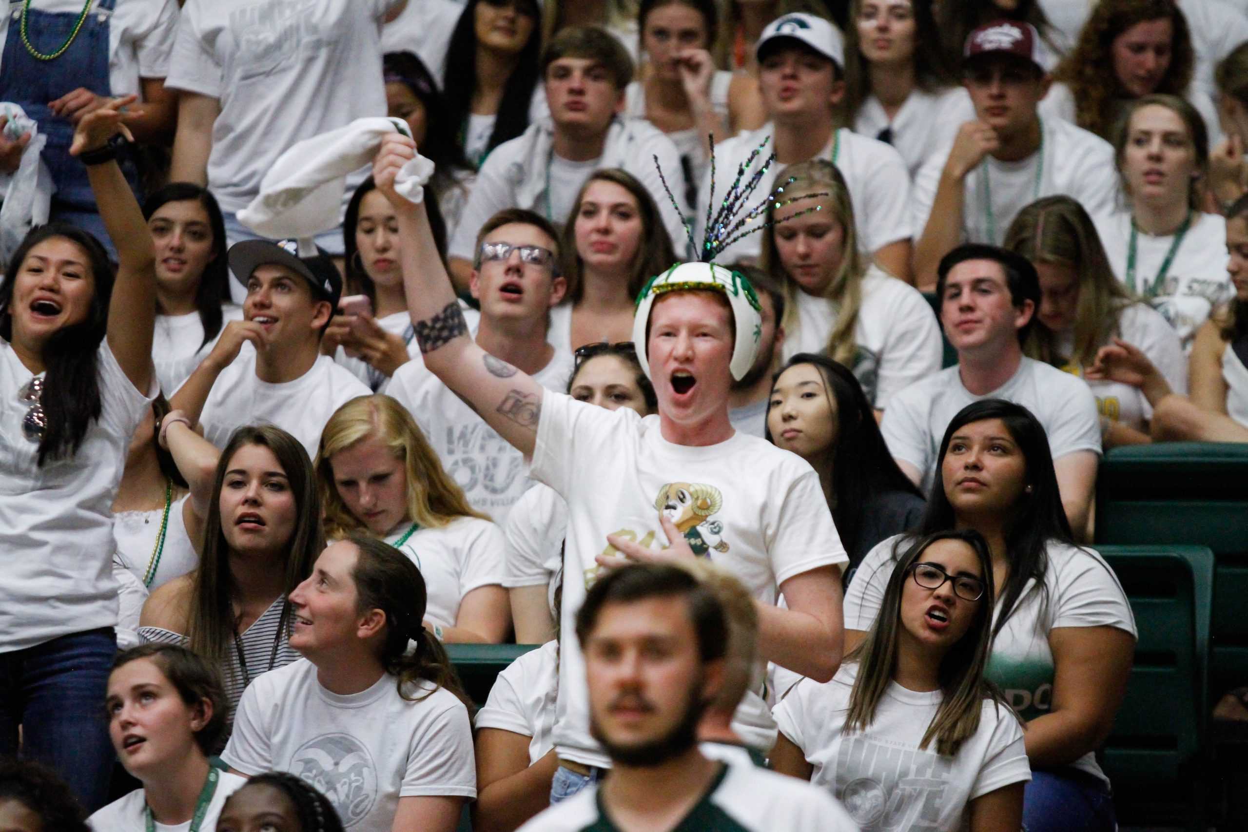 a fan cheers while wearing a volleyball hat